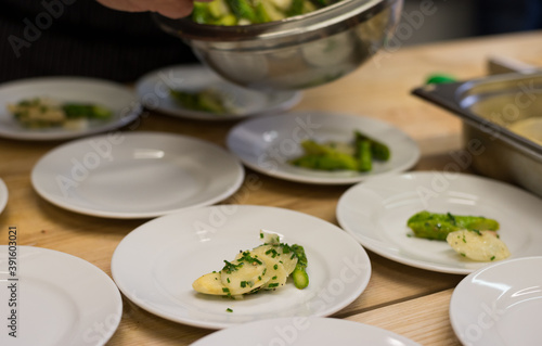 Plating slices of white and green asparagus on small plates as starter dish
