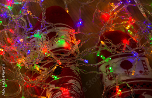 Feet In Christmas Socks In Front Of Christmas Lights. Christmas Backgrounds.