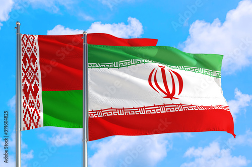 Iran and Belarus national flag waving in the windy deep blue sky. Diplomacy and international relations concept.