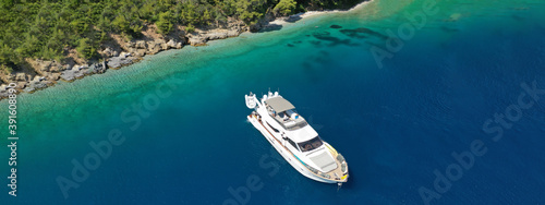 Aerial drone ultra wide panoramic photo of luxury yacht anchored in tropical exotic island with crystal clear turquoise sea and pine trees