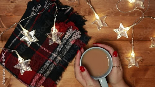 a woman warms her hands on a mug of hot chocolate