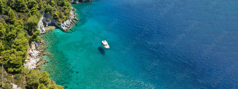 Aerial drone ultra wide panoramic photo of traditional wooden fishing boat anchored in Ionian island turquoise sea, Greece