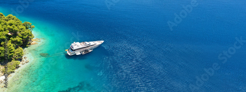 Fototapeta Naklejka Na Ścianę i Meble -  Aerial drone ultra wide panoramic photo of luxury yacht anchored in tropical exotic island with crystal clear turquoise sea and pine trees