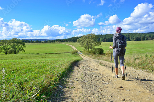 Backpacker woman hiking on the country road. Beautiful nature around them. Outdoor activity and walking in the countryside. © Jurek Adamski