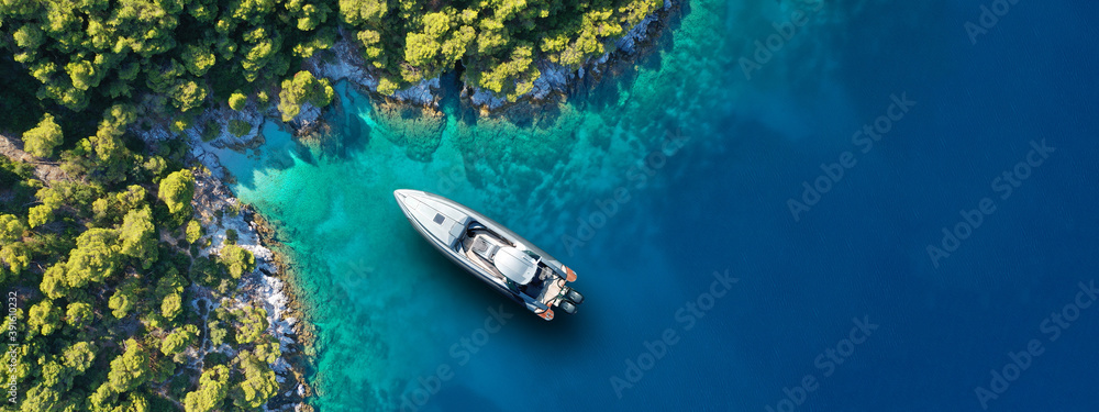 Aerial drone ultra wide panoramic photo of luxury yacht anchored in tropical exotic island with crystal clear turquoise sea and pine trees