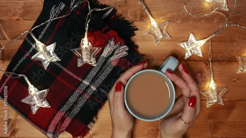 a woman warms her hands on a mug of hot chocolate