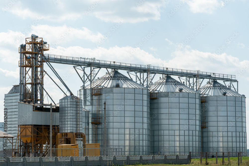 silver silos on agro manufacturing plant for processing drying cleaning and storage of agricultural products, flour, cereals and grain. Large iron barrels of grain. Granary elevator silver silos on agro manufacturing plant for processing drying cleaning and storage of agricultural products, flour, cereals and grain. Large iron barrels of grain. Granary elevator