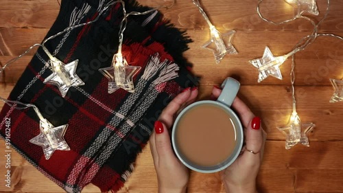 a woman warms her hands on a mug of hot chocolate