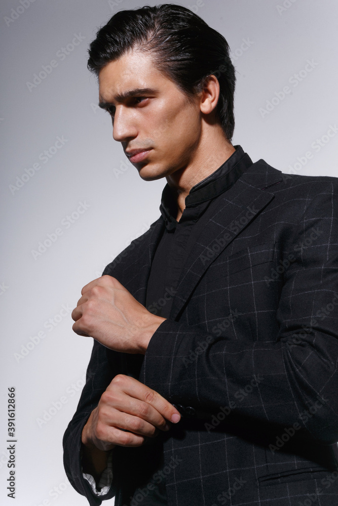 Close Up portrait of a handsome serious young man in black suit over white dark background. Vertical view. Close Up portrait of a handsome serious young man in black suit over white dark background. Vertical view.