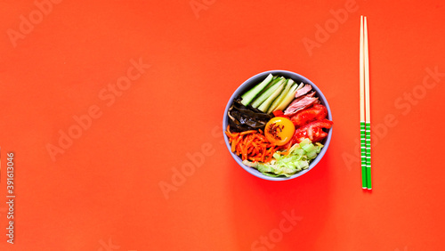 Traditional dish of Korean cuisine. Bibimbap with beef, vegetables and egg on coral background. Top view.