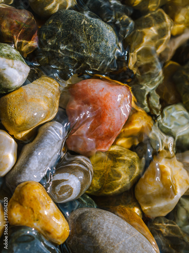 Fototapeta Naklejka Na Ścianę i Meble -  Colorful sea pebbles in the water and reflections closeup
