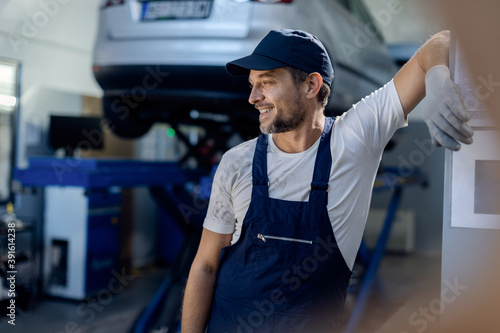 Smiling mechanic relaxing taking a break from work at auto repair shop.