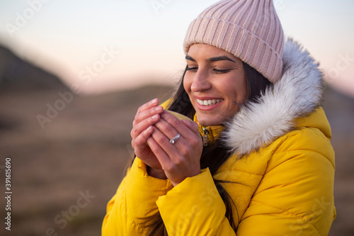 Portrait of a smiling woman drinking hot drink at the could mountains.