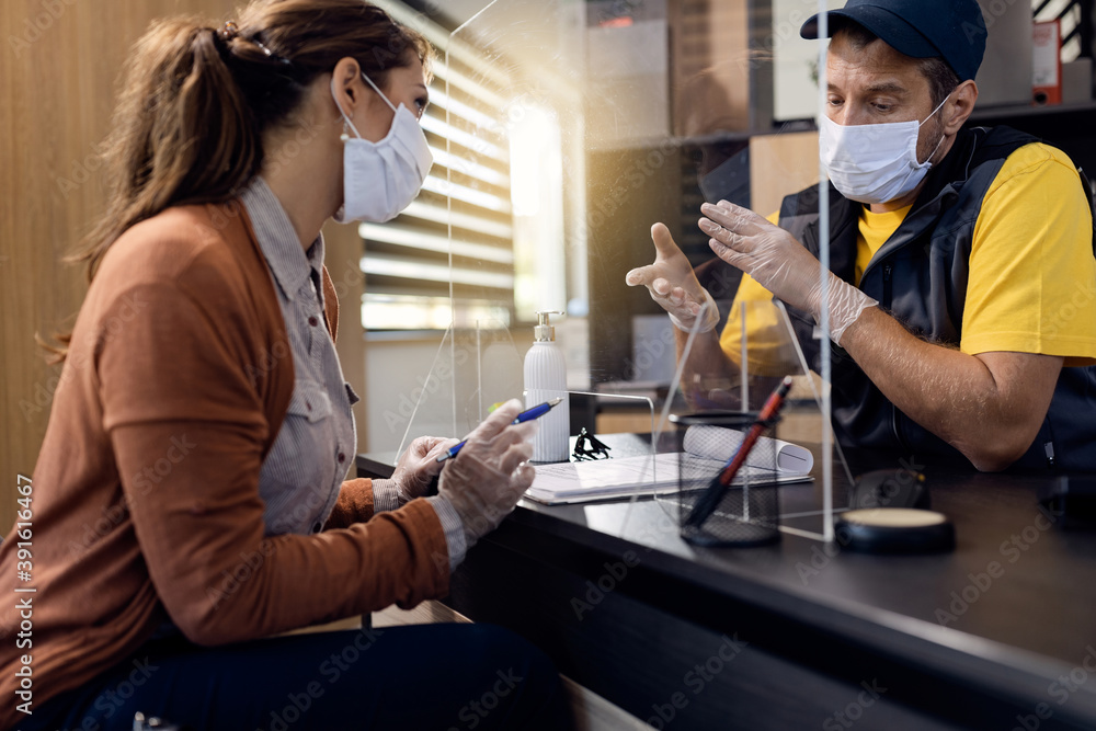Fototapeta premium Auto repairman communicating with a customer while wearing protective face mask and gloves in the office.