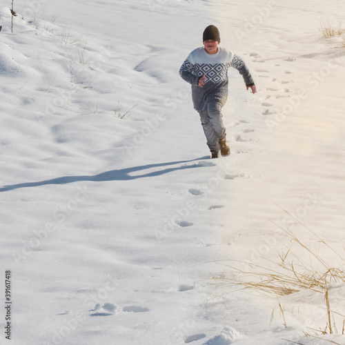 young boy running playing in the snow on a sunny day, happy with the cold © CarloslVives