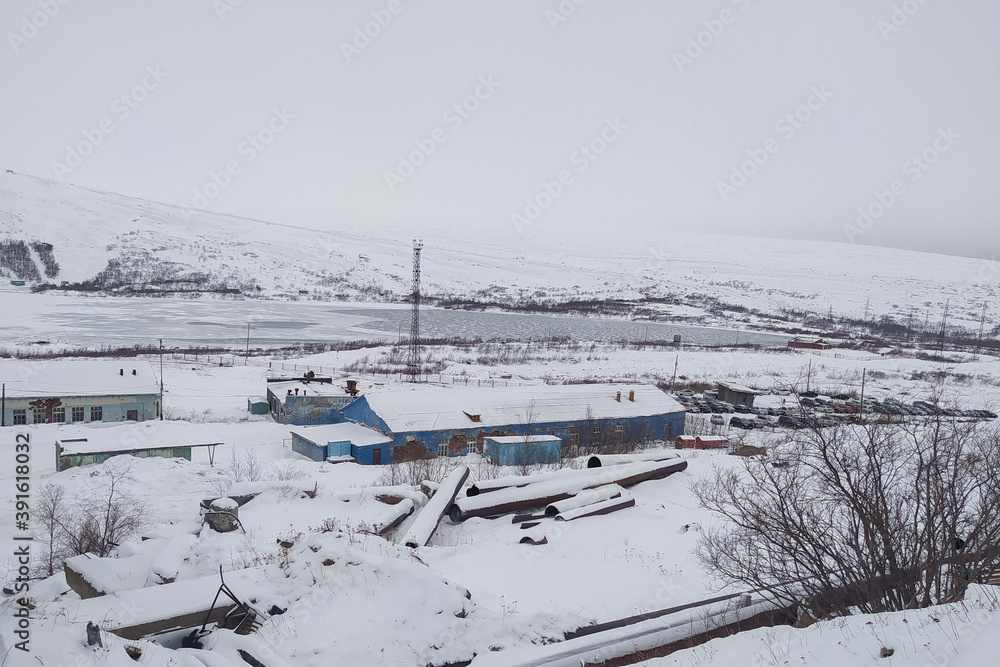 Obraz premium one-story blue building in the snow on the background of mountains in the fog in winter