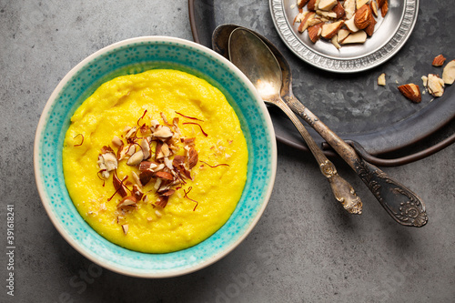 Traditional Indian dish Kheer, sweet rice milk pudding with almonds and saffron in blue ceramic bowl with spoons on stone rustic background, top view. Dessert meal of Indian cuisine photo