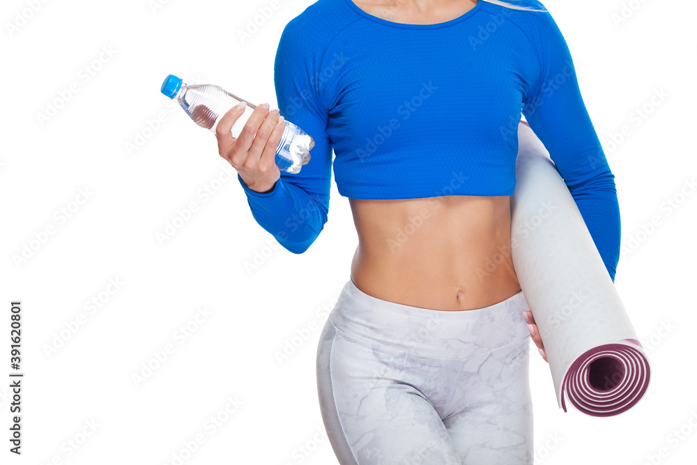 Close up shot of attractive sportswoman abs with a bottle of mineral water and a mat in her hands isolated on white background Close up shot of attractive sportswoman abs with a bottle of mineral water and a mat in her hands isolated on white background