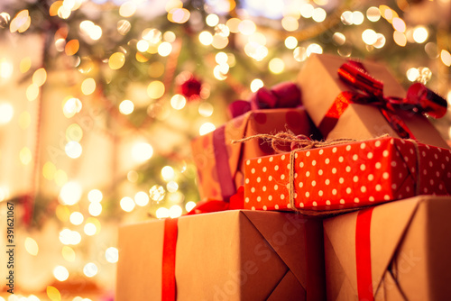 Christmas presents under the tree, full of bright lights of garland. Warm cozy atmosphere, new year miracles spirit in the air.