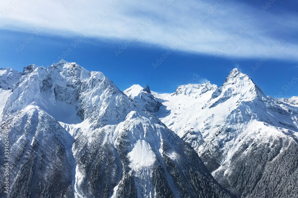 high snowy peaks of Caucasian mountains and blue sky with clouds over it. Breathtaking view.