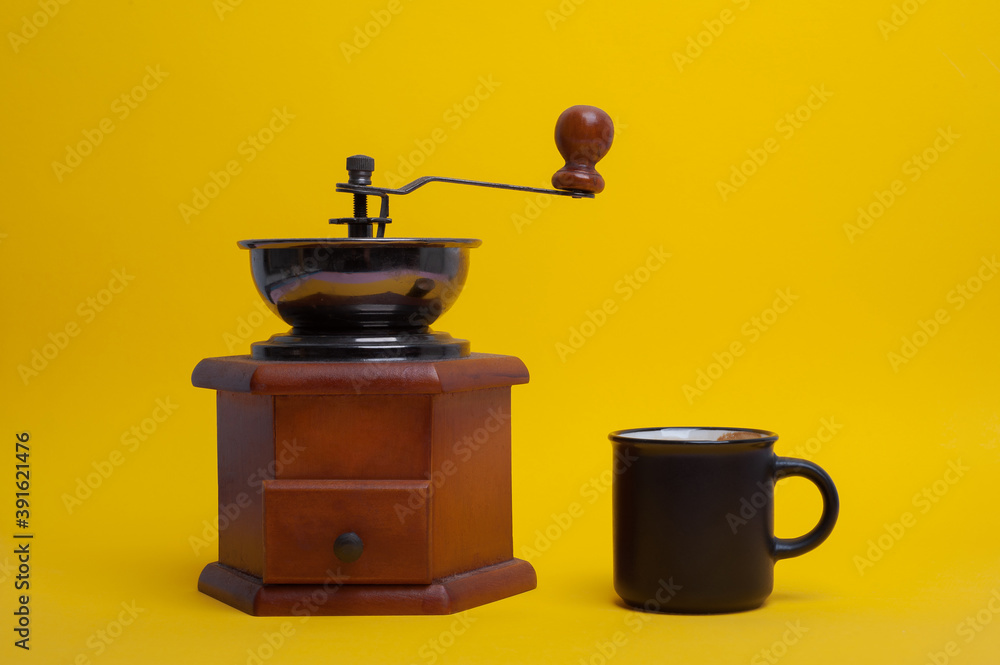 coffee cup and manual coffee grinder on yellow background coffee cup and manual coffee grinder on yellow background
