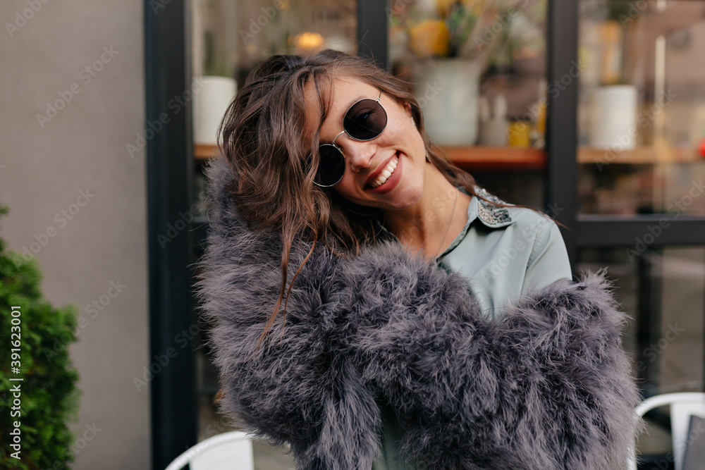Excited charming woman with wavy hair dressed fur coat in glasses posing at camera Excited charming woman with wavy hair dressed fur coat in glasses posing at camera