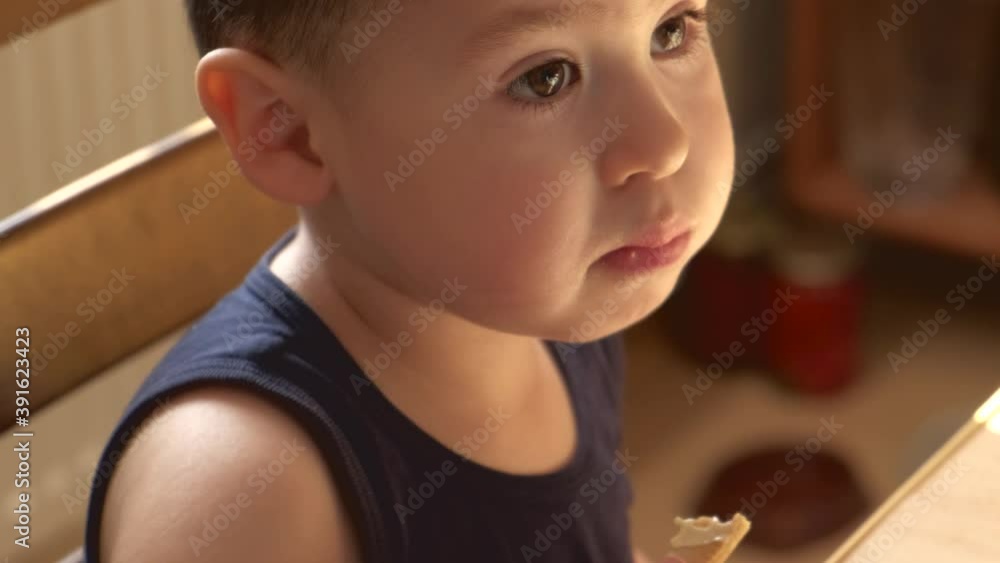 Close up video of an adorable boy eating breakfast at the table drinking milk and looking at something Close up video of an adorable boy eating breakfast at the table drinking milk and looking at something