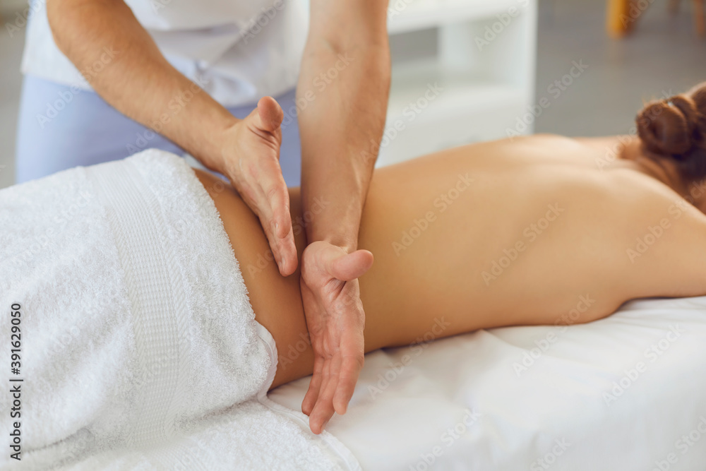Hands of a male masseur knead the muscles of a woman's back in a massage parlor. Hands of a male masseur knead the muscles of a woman's back in a massage parlor.