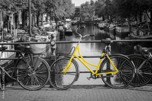 A fresh yellow bike on the streets of Amsterdam. Symbol for clean and ecological urban transport. Isolated in a black and white background. 