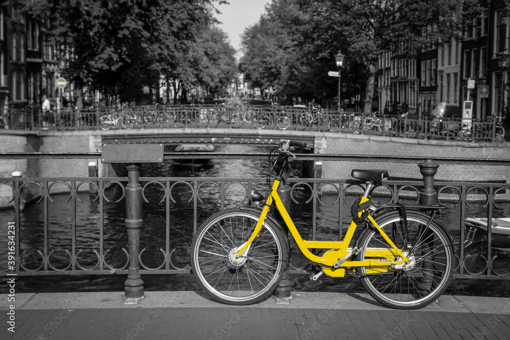A fresh yellow bike on the streets of Amsterdam. Symbol for clean and ecological urban transport. Isolated in a black and white background. 