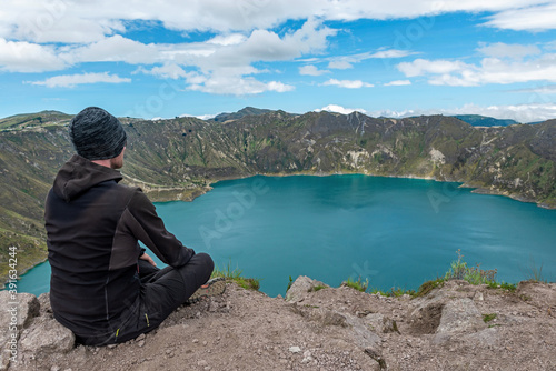 A middle aged backpacker looking over the Quilotoa volcanic crater lagoon, south of Quito, Ecuador.