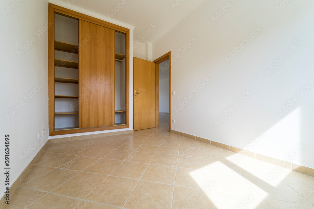 Fototapeta premium Empty room with dark wooden floating laminate flooring and wardrobe. House interior, wide bedroom space. Newly recently painted new apartment or house. Wood floor. Real state and property management