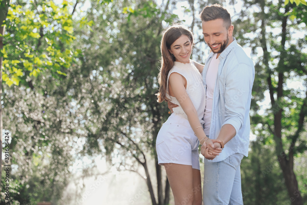 Fototapeta premium Lovely young couple dancing together in park on sunny day