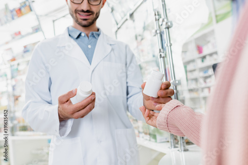 cropped view of pharmacist giving bottle with pills to customer in drugstore Fototapet