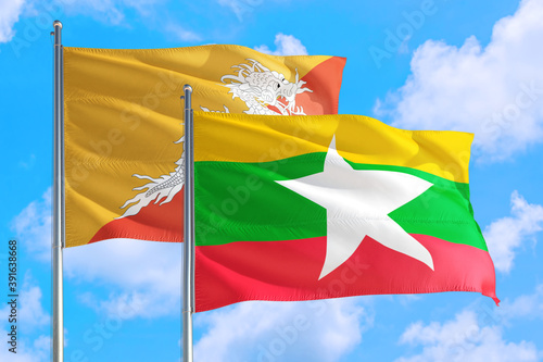 Myanmar and Bhutan national flag waving in the windy deep blue sky. Diplomacy and international relations concept.