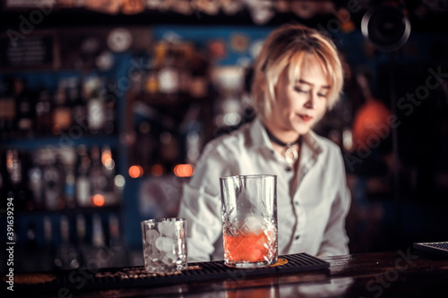 Girl bartender mixes a cocktail on the porterhouse