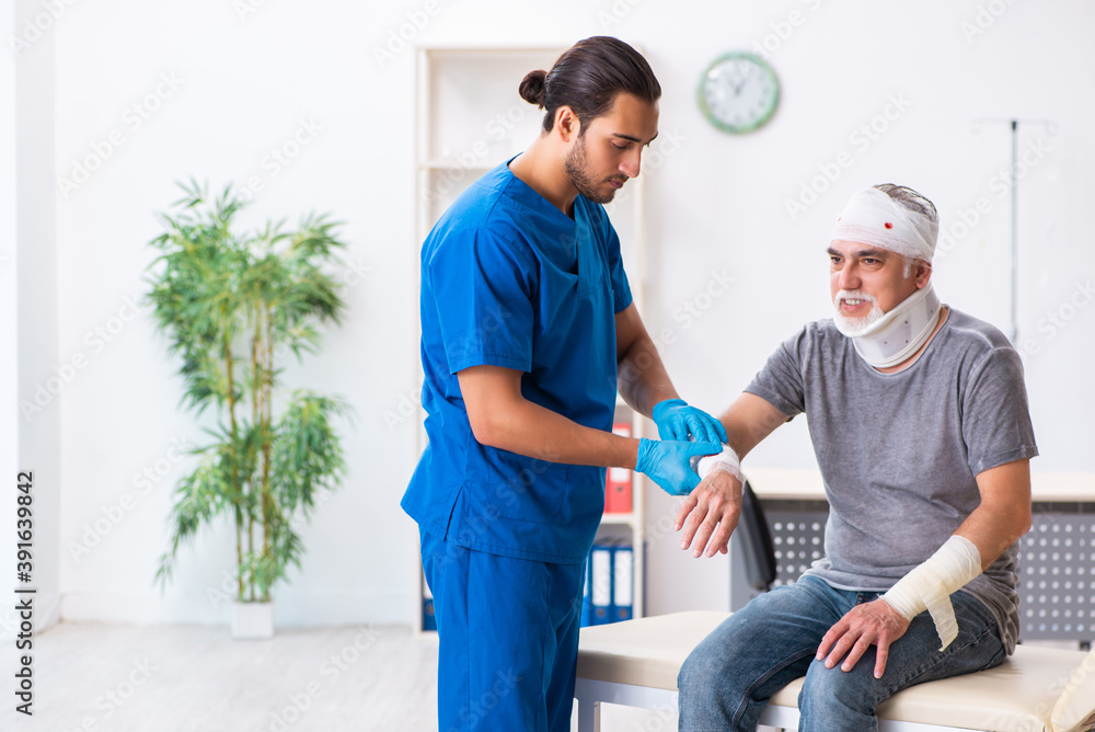 Young male doctor and old patient in first aid concept Young male doctor and old patient in first aid concept