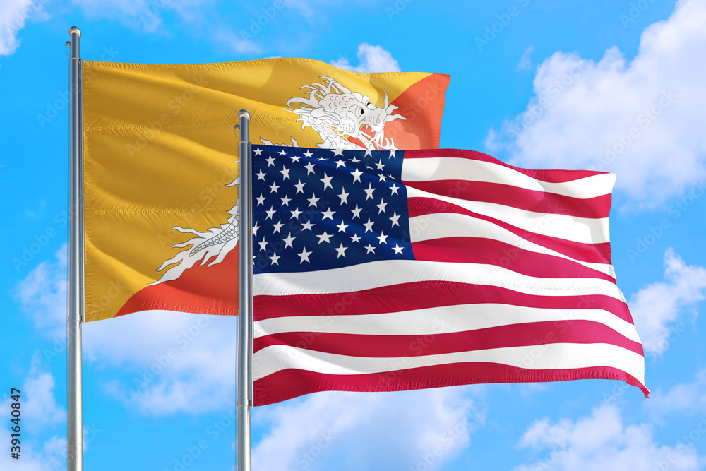United States and Bhutan national flag waving in the windy deep blue sky. Diplomacy and international relations concept.