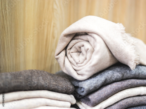 pile of clothes, rolled beige cashmere blanket, Knitting cashmere wool yarn, closeup beige blanket, home decor, closeup rolled beige cashmere woollen blanket, soft selective focus, copy paste concept © Lesia Povkh
