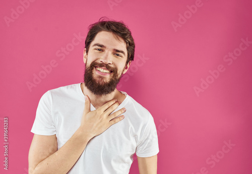 Enthusiastic man in a white T-shirt with a bushy beard on a pink background
