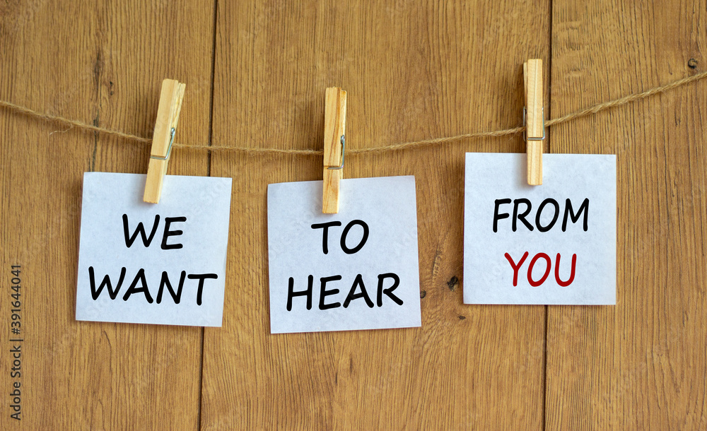 Wooden clothespins with white sheets of paper. Text 'we want to hear from you'. Beautiful wooden background. Business concept, copy space. Wooden clothespins with white sheets of paper. Text 'we want to hear from you'. Beautiful wooden background. Business concept, copy space.