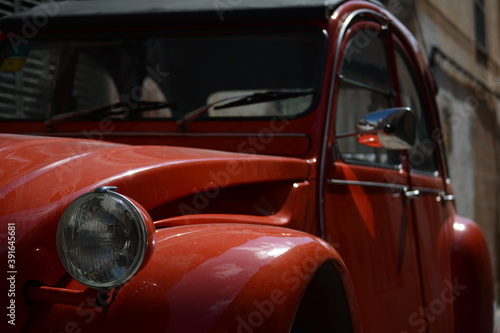 Detalle del faro de un coche antiguo rojo © Pere