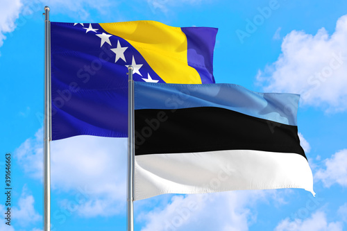 Estonia and Bosnia Herzegovina national flag waving in the windy deep blue sky. Diplomacy and international relations concept.