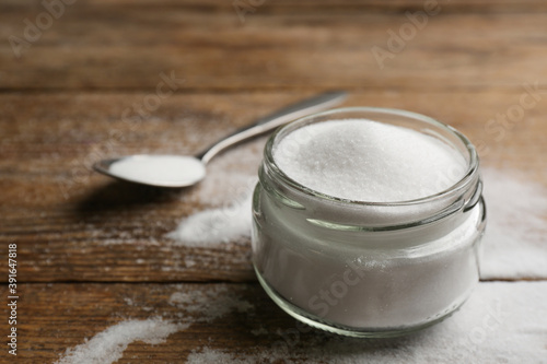 Glass jar with salt on wooden table, closeup