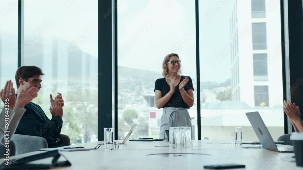 Business people clapping hands in office conference room. Group of people clapping happily while celebrating success in boardroom.
