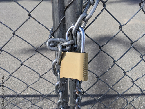 yellow padlock and chain keeping a chainlink fence sealed
