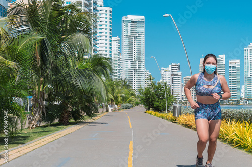 Woman in a medical mask running through a park. Concept of fitness