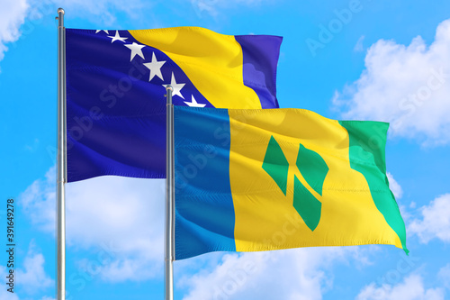 Saint Vincent And The Grenadines and Bosnia Herzegovina national flag waving in the windy deep blue sky. Diplomacy and international relations concept.