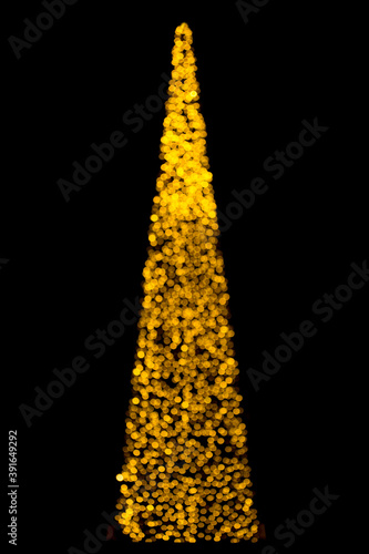 Defocused christmas tree silhouette with blurred lights.Bokeh silhouette of Christmas tree.Christmas and New Year background with golden blur