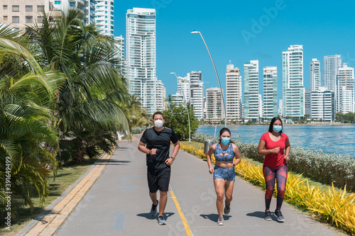 A group of young athletes with protective masks running in the park Fitness concept